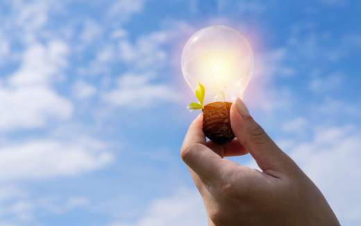 Photo de lactivité scolaire science : transformation des énergies, montrant une main en gros plan qui tient une ampoule vers le ciel bleu