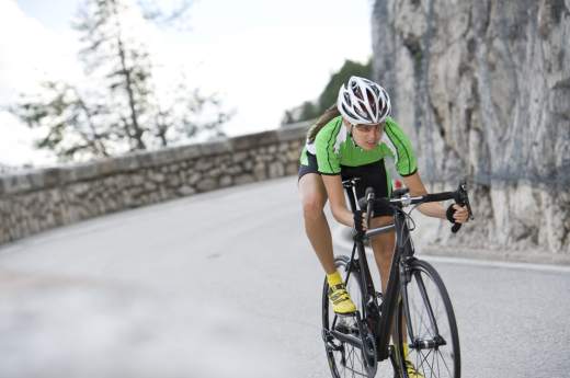 Femme pratiquant le cyclisme sur une route de montagne illustrant la rubrique cyclisme sur route